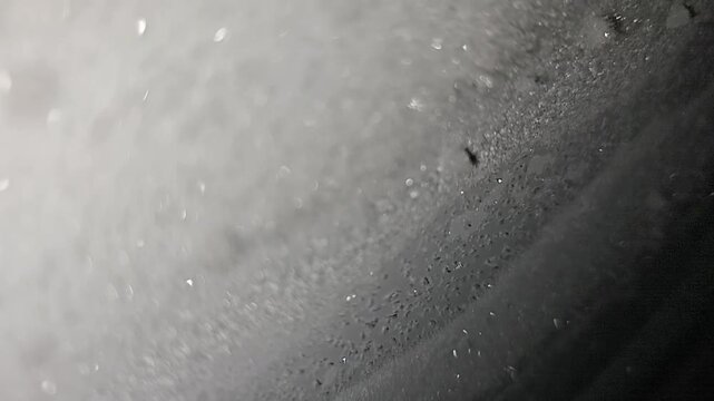 Close-up abstract macro footage featuring a dark frosted surface with subtle sparkling highlights and soft cinematic focus. Ideal for background overlays, moody edits, sci-fi visuals, title sequences,