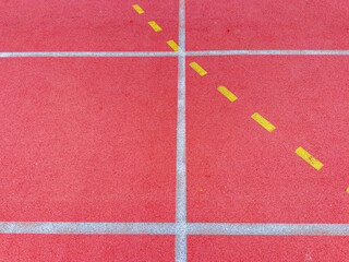Fototapeta premium Red track surface with yellow lines for lane markings and white lines for distance in a sports facility