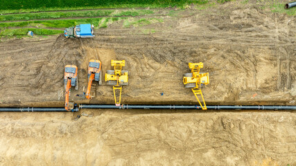 Aerial view of a major pipeline construction project. Heavy machinery including excavators and pipelayers install a new gas line in a rural field. Industrial energy infrastructure development. © dechevm