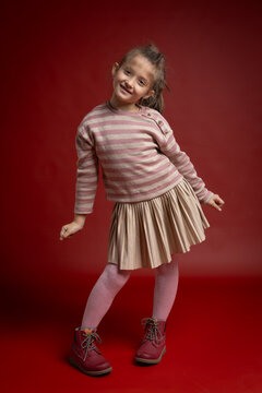 Smiling Little Girl Posing in Studio. Full Length Child Portrait with Playful Expression and Fashionable Clothing