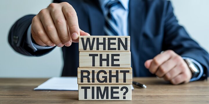 A man in a suit holding wooden blocks with the phrase When The Right Time