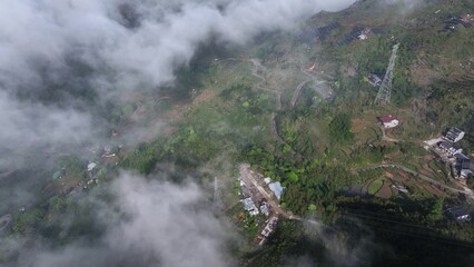 Fototapeta premium Aerial view of mountain terraced fields and village shrouded in mist