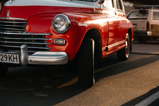 vintage GAZ-20 Pobeda in rays of setting sun. Two-tone red and white 1940s soviet car with chrome grille and round headlight parked with turned wheel at evening car meet. Kyiv, Ukraine - May 16 2026
