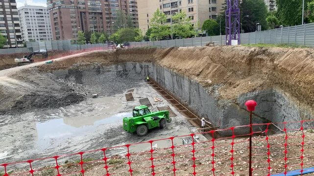 Construction progress overview: exposed foundations and emerging structure.