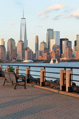 Obraz premium Serene Waterfront Scene. Calm Lakeside With Empty Benches And Sailboats Nearby new york