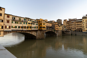 Obraz premium The historic Ponte Vecchio bridge in Florence, Italy, spans the Arno River with its iconic shops and architecture