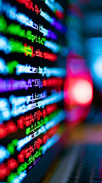 Abstract close-up of colorful programming code on a computer screen with a blurred laptop keyboard in the foreground.