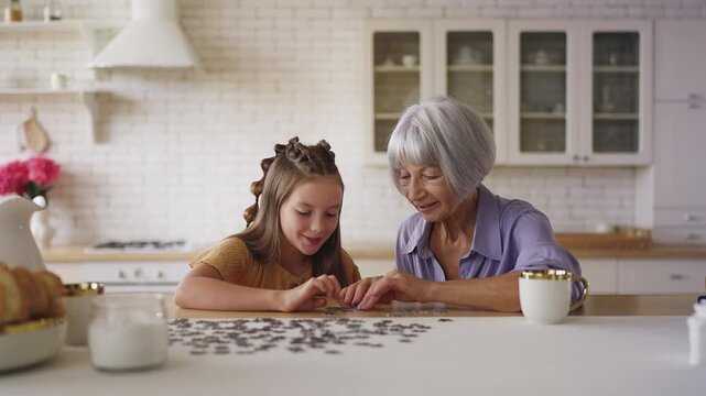 Happy girl and her grandmother connecting jigsaw puzzle pieces, family bonding