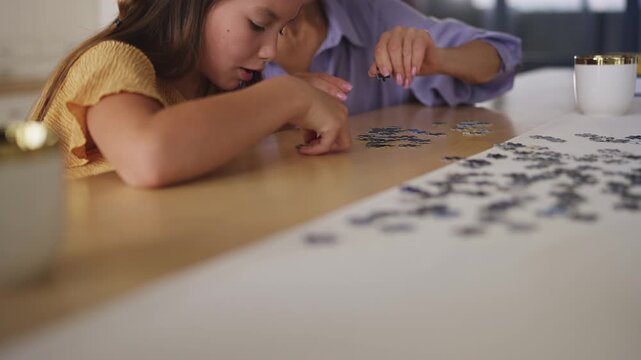 Senior woman and her grandchild connecting jigsaw puzzle pieces, family bonding