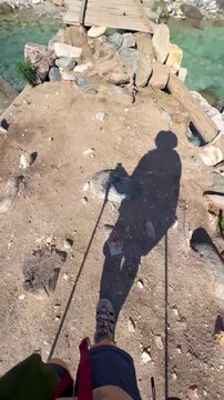 The video shows a hiker filming their own feet walking on an old wooden bridge in Xinjiang, China. A stream with clear, blue water flows from the glacier.