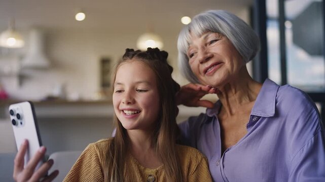 Happy senior woman and her grandchild talking with family during video call