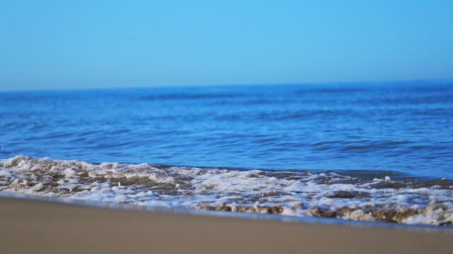 Beautiful sea surf and blue sky creating a peaceful summer beach scene in 4K slow motion.