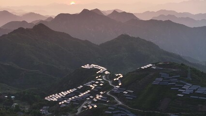 Fototapeta premium Morning mist and sunrise over terraced fields and village in Guizhou mountains