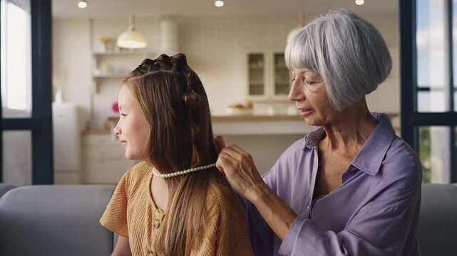 Senior woman gifting meaningful necklace to young granddaughter, heirloom gift
