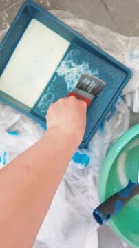 Person priming interior wall with brush using primer