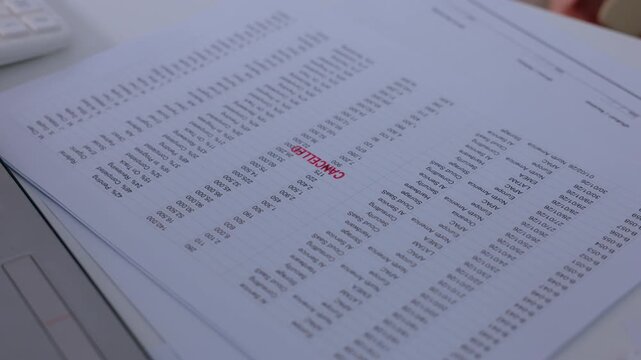 Reviewing and stamping printed paper document containing text chart graphic detail showing financial business data report for administrative approval process on corporate office desk