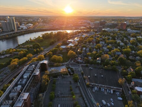 Golden hour aerial drone view of the Boston skyline, featuring the Prudential and John Hancock towers rising above the historic Back Bay neighborhood and the calm waters of the Charles River