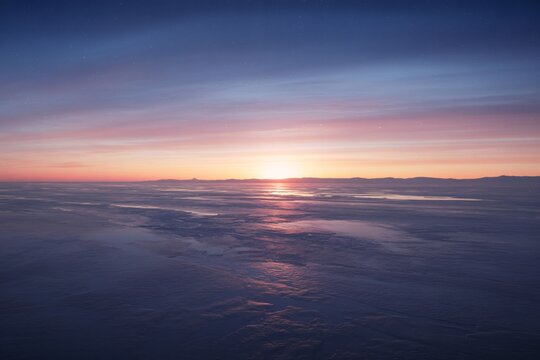 Vibrant sunset over ocean with sun rays piercing through dark clouds