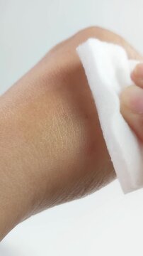 Cleaning hand skin with cotton pad removing cosmetic stain. Top view of hand on white background. Hygiene and self care concept.