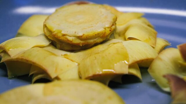 Artichoke flower frying in a hot pan, traditional Spanish dish flor de alcachofa. Close-up cooking process. Mediterranean cuisine concept. High quality 4k footage