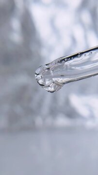 Clear liquid dripping from transparent pipette tip serum freshness concept macro