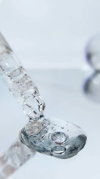 Close up serum pipette with bubbly liquid. Beauty liquid on glass reflection blurred background