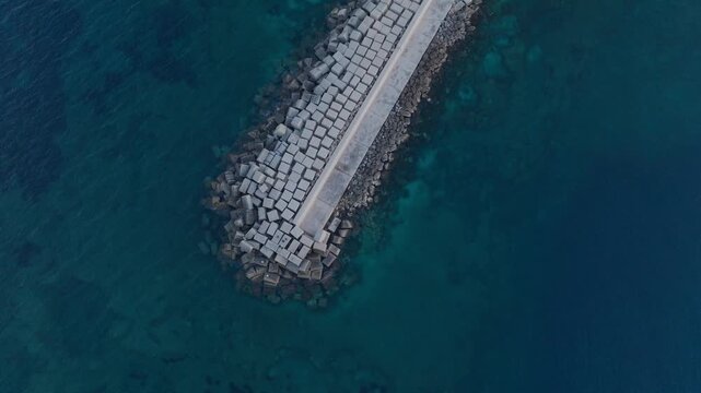 Aerial view of the concrete block breakwater and turquoise sea at the Island of Ortigia in Syracuse, Sicily, Italy.