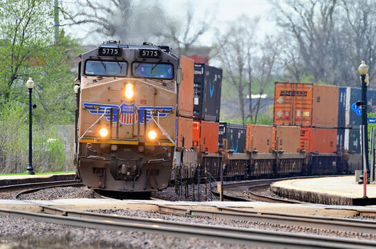 An eastbound Union Pacific Railroad intermodal freight train negotiaties a curve while passing between deserted commuter rail station platforms in Chicago's western suburbs.