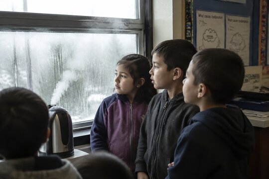 Students watching steam from a kettle condense on a window. Educational science experiment focusing on physical states. Ideal for educational materials and school blogs.