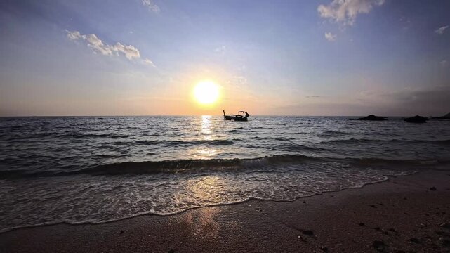 Small boat silhouette on calm sea at sunset with golden horizon