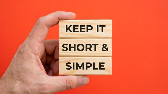 A hand holding wooden blocks with the words keep it short and simple written on them against a bright red background for a business concept