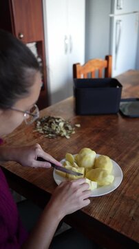 Woman cutting potatoes at home kitchen table