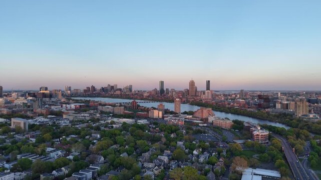 Golden hour aerial drone view of the Boston skyline, featuring the Prudential and John Hancock towers rising above the historic Back Bay neighborhood and the calm waters of the Charles River.