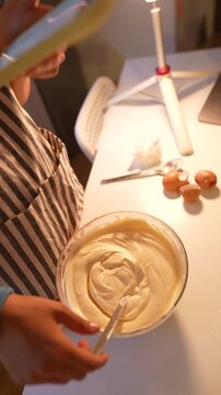 Caucasian woman home baker reading recipe on phone while mixing batter