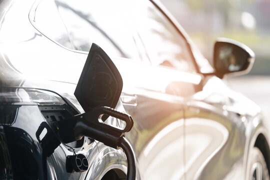 Electric vehicle plugged into charging station at curbside, technology for hybrid car in China
