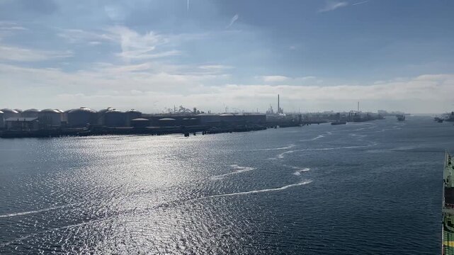 A port terminal with tanks for storing petroleum products, cargo cranes and windmills.