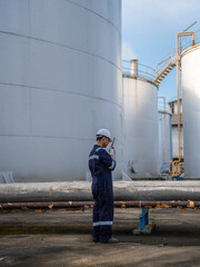 Obraz premium Petrochemical Engineers checking reports for technical inspections in oil refinery. Technicians working on checklist in the oil storage tank area. Factory and industry manufacturing. Oil tank