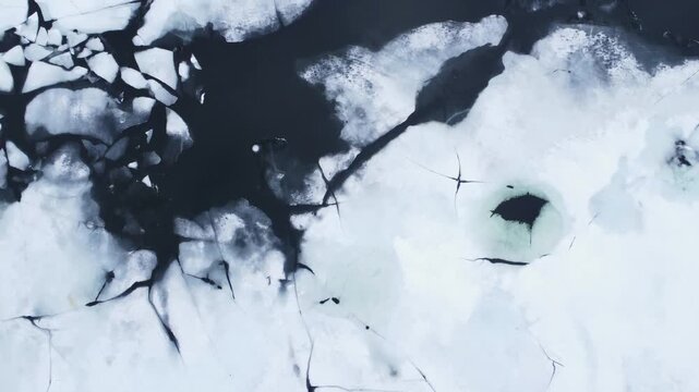 Aerial view of abstract patterns of cracked ice and dark water on the Hardangervidda plateau in Ullensvang, Vestland, Norway.