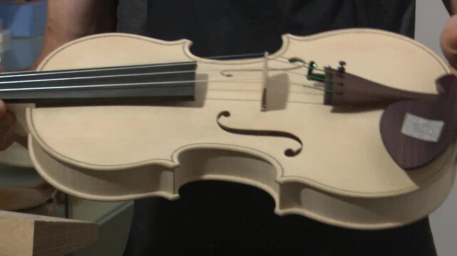 Bilbao, spain; may 21 2022: luthier assembling bridge on handmade wooden violin