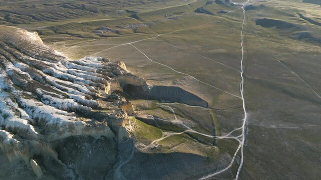 Drone view of Mount Sherkala from the side where the cliff is heavily eroded by weather. Unique geology of Mangystau, endless desert of Kazakhstan, Martian landscapes, weathered limestone formations, 