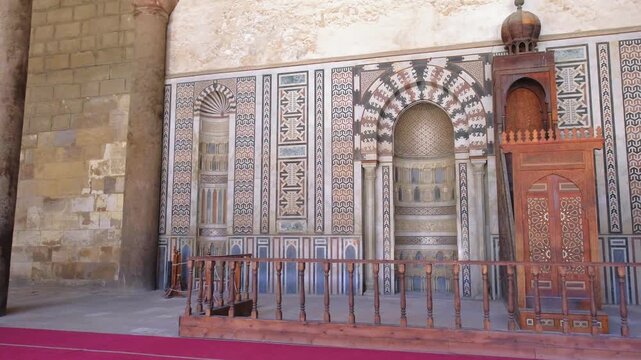 Slow motion panoramic view of ornate Islamic prayer wall and wooden minbar inside historic mosque in Cairo, Egypt. Ancient Arabic architecture and decorative patterns in 4K travel footage.