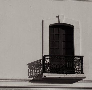 Colonial architecture: detail of a window with an iron grille and side shadows.