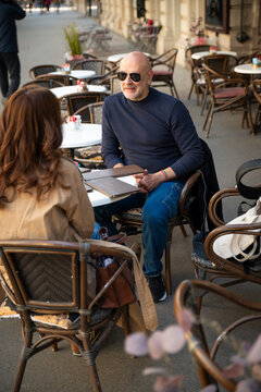 Mature couple enjoying conversation at an outdoor sidewalk cafe