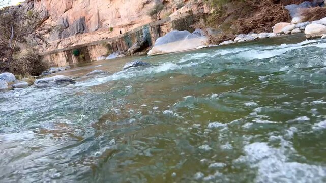 Flowing stream at Wadi Tanuf in Nizwa with clear water, rocks and canyon walls showcasing Omani valley nature. Nizwa, Oman - May 4 2026