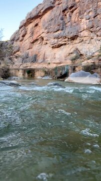 Flowing stream at Wadi Tanuf in Nizwa with clear water, rocks and canyon walls showcasing Omani valley nature. Nizwa, Oman - May 4 2026