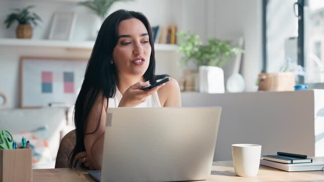 Video of beautiful woman using smartphone while working with laptop in the livingroom at home