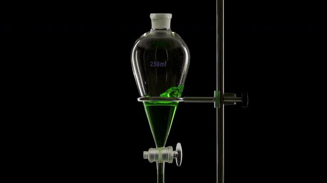 Close shot of green transparent fluid is injected into a separatory funnel, producing splashes within the liquid placed on a black background