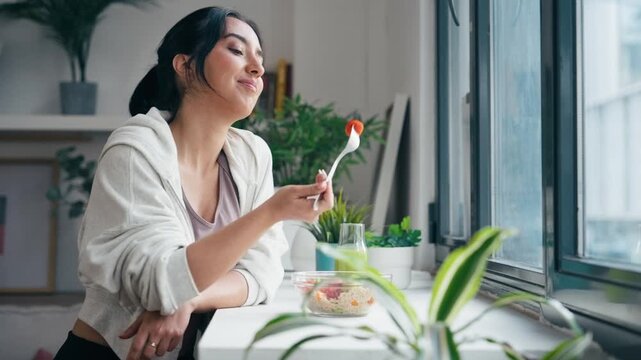 Video of cute woman eating a healthy poke bowl in the kitchen at home