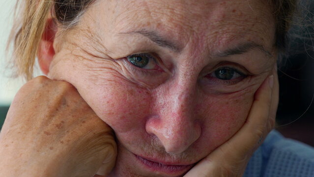 Elderly woman with worried and suspicious expression resting her head on hands, close up portrait conveying doubt, vulnerability, and emotional tension of aging