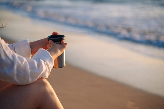 Person with hand malformation enjoying coffee at beach